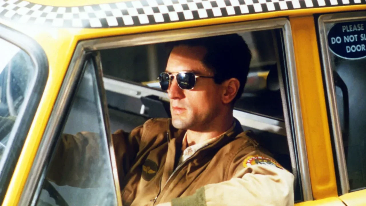 Man wearing sunglasses driving a yellow taxi