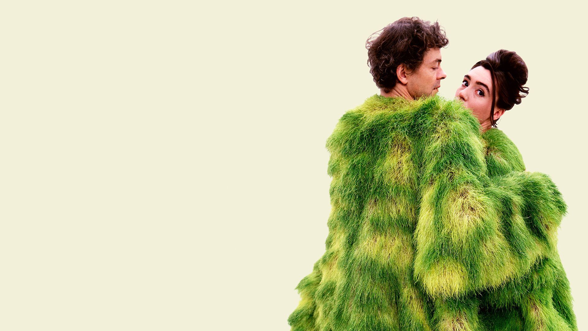 Young man and woman holding each other with a big green blanket around them