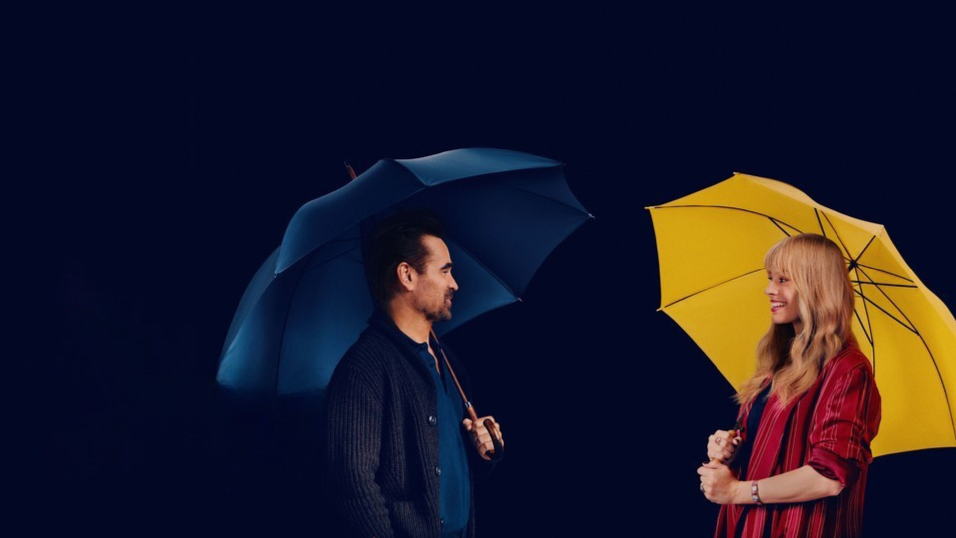 Photo of a man under a blue umbrella and a woman under a yellow umbrella