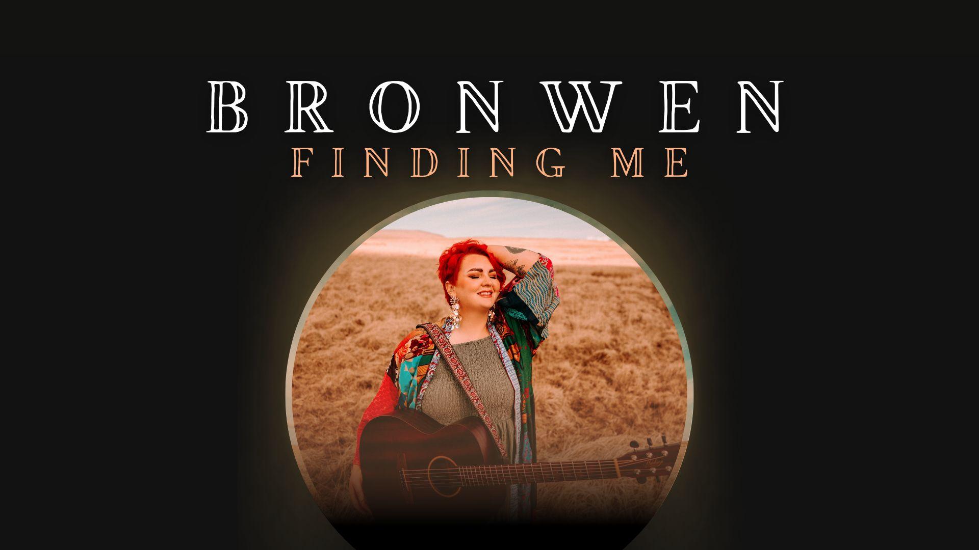 Photo of Bronwen Lewis with guitar on a beach