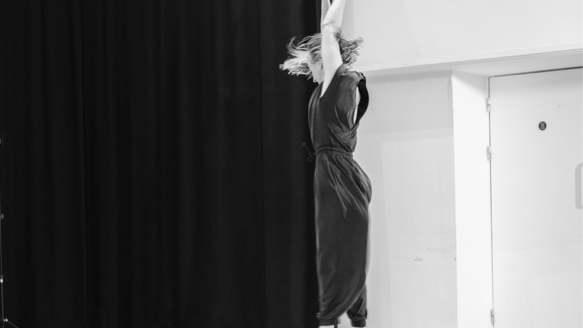 black and white image of woman dancing, jumping in the air with arms stretched