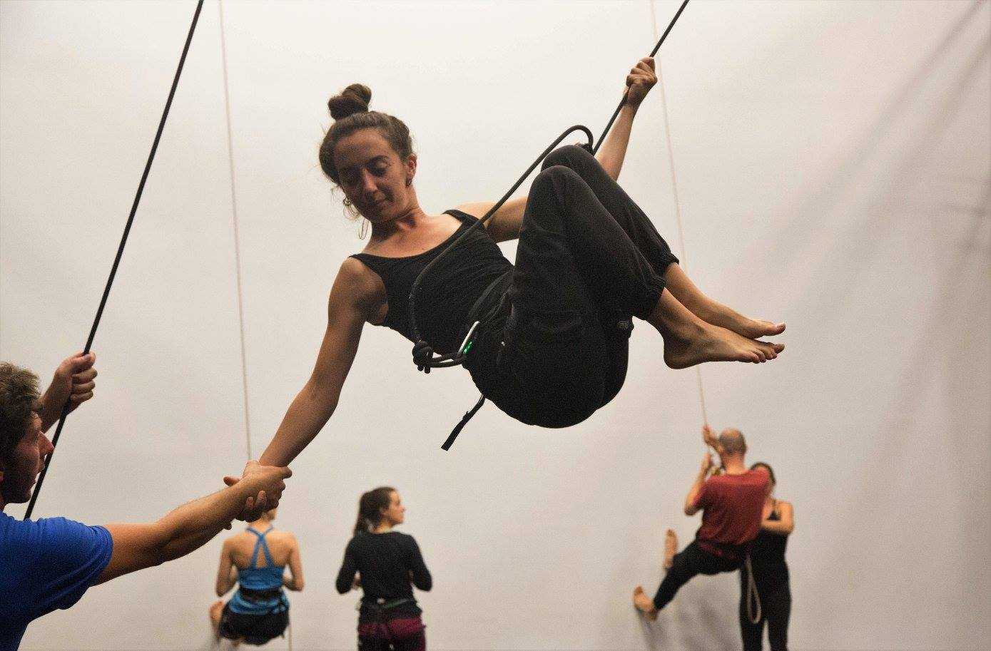 Photo of a woman in a harness flying and other climbing a wall
