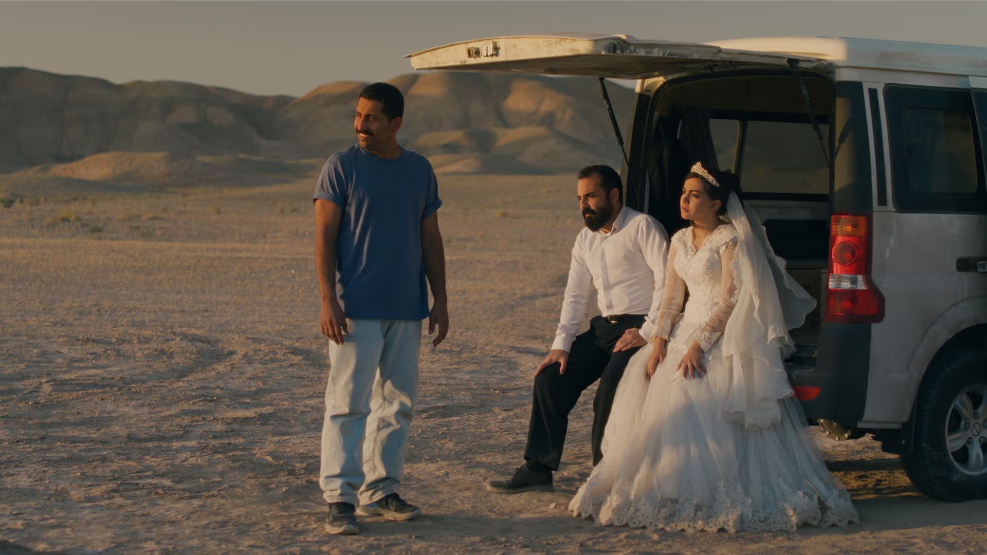 Bride and groom sitting in the back of a van in the middle of the dessert