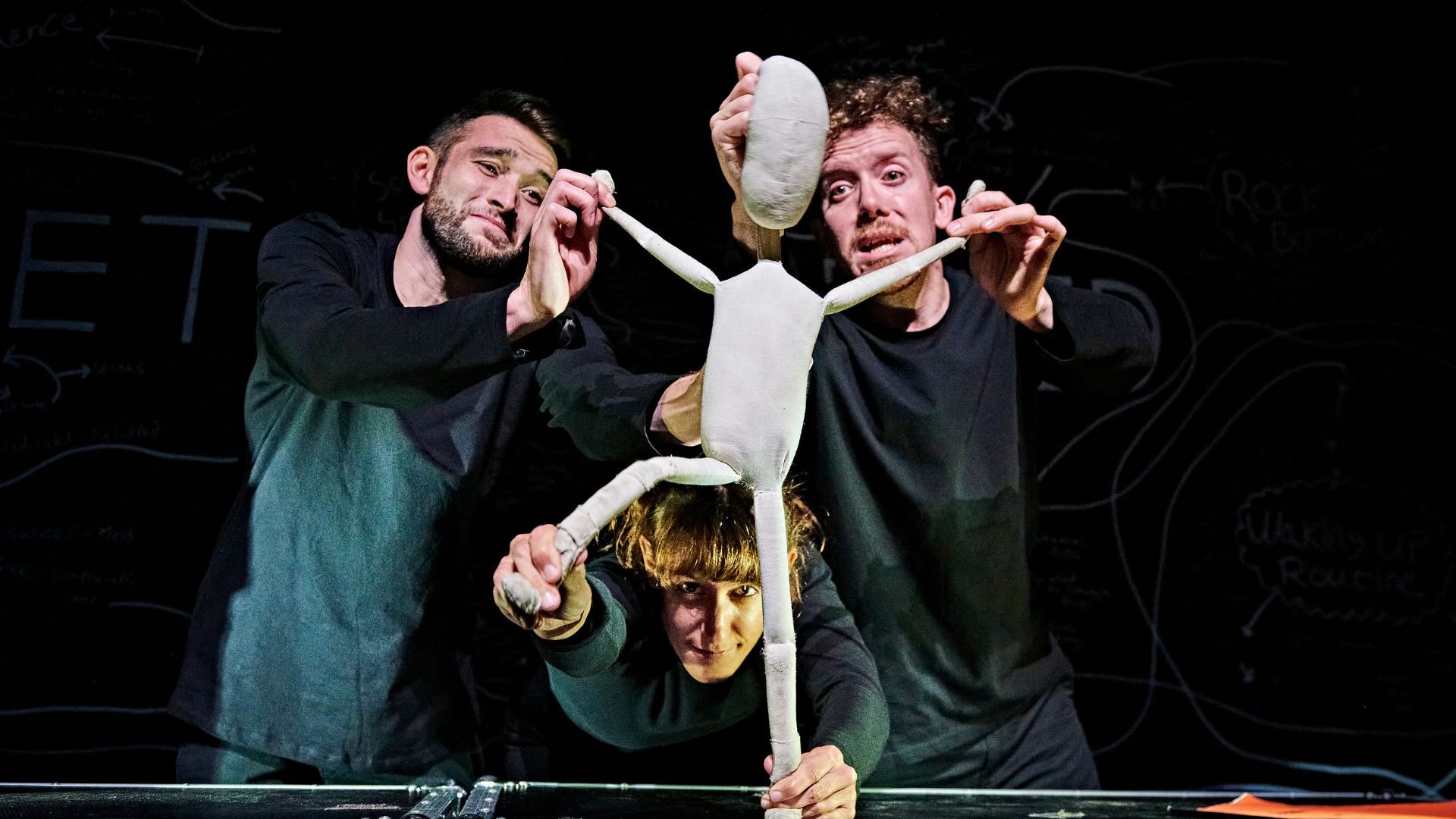 three people holding a human figure puppet