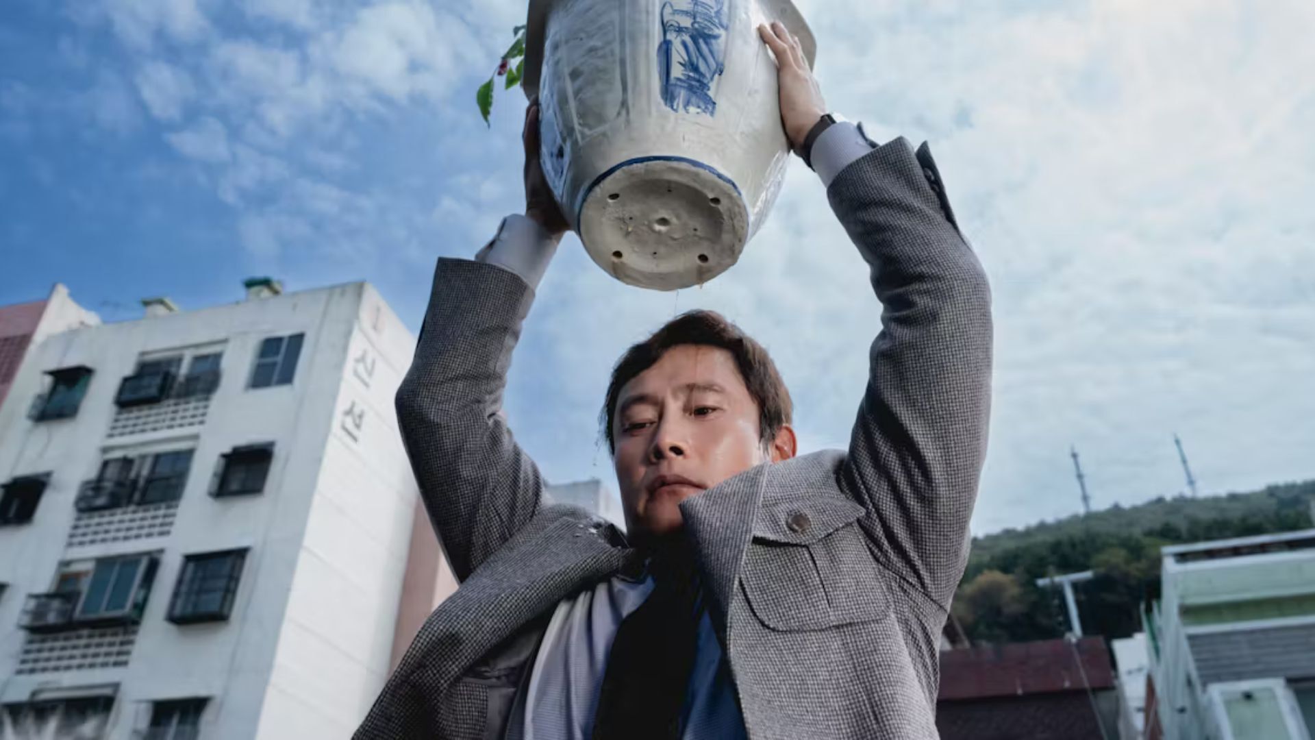 Man holding a plant pot above his head as if he is about to throw it on the floor