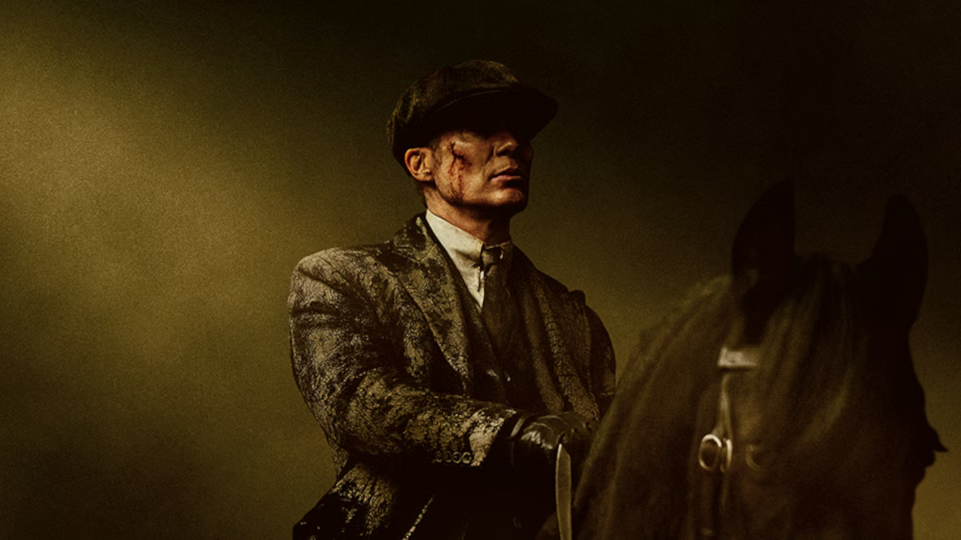 Image of actor Cillian Murphy as Tommy Shelby wearing dark clothing, and blood on his face riding a black horse
