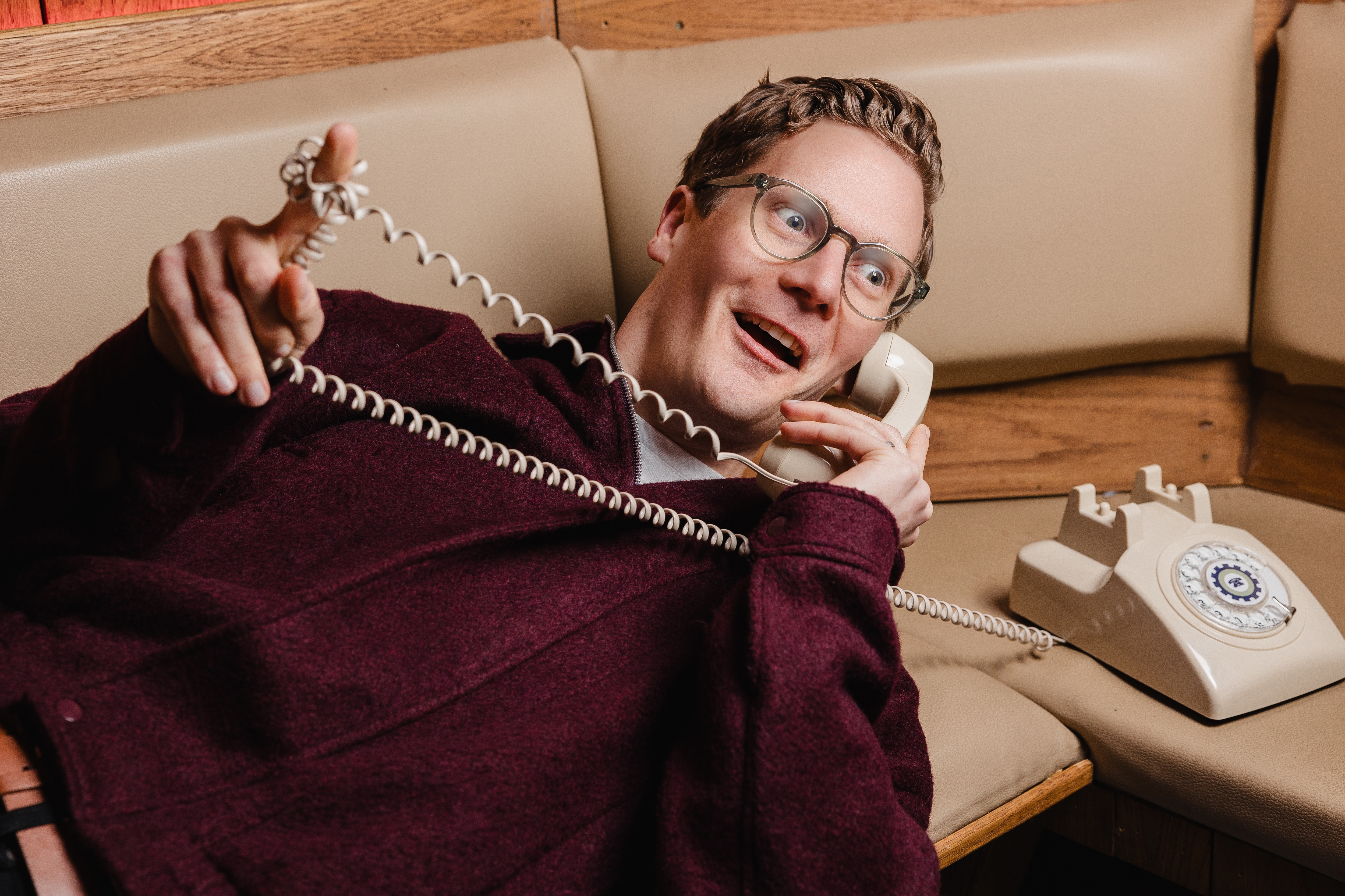 Robin Morgan lying on a sofa and smiling whilst talking on an dial phone