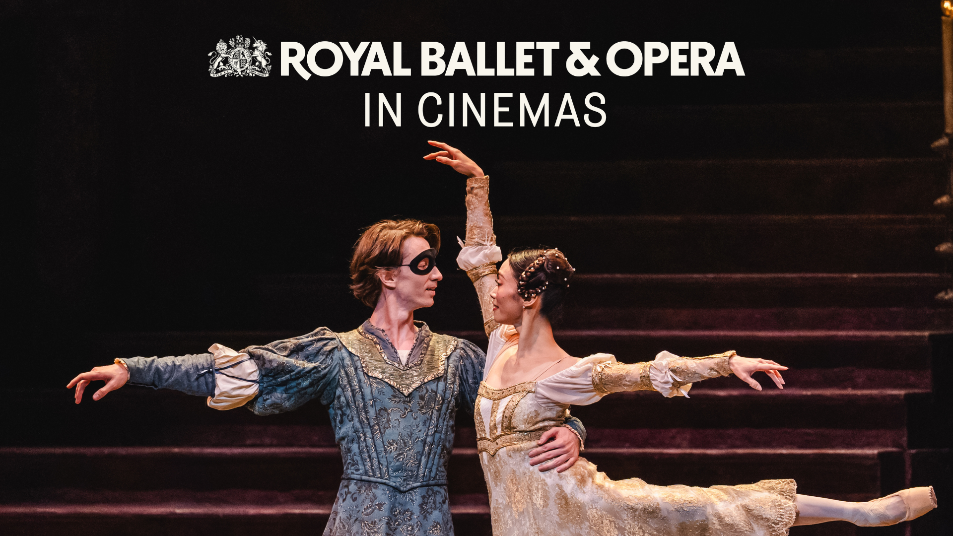 Two ballet dancers a male in blue wearing a mask and a woman in light clothing facing each other, he has his arm around her waist