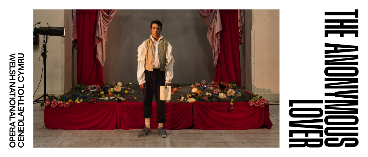 Photo of a man standing in front of a small stage with flowers thrown all over the stage
