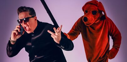 Man dressed in black on the phone with someone dressed up as a dog coming after him