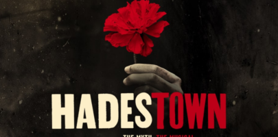 HADESTOWN text in bold white and blood red lettering, on a black background with a hand holding a red flower