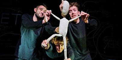 three people holding a human figure puppet