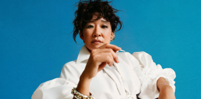 Actor Sandra Oh wearing a white shirt standing in front of a light blue background