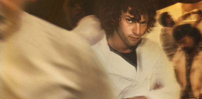 Man looking very serious in a busy kitchen wearing white kitchen attire