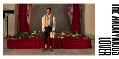 Photo of a man standing in front of a small stage with flowers thrown all over the stage