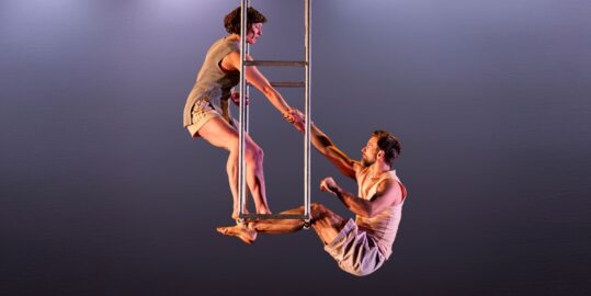 Man and woman doing aerial work with dark grey background