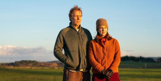 Man and woman standing outside in the countryside during sunset on a cold day
