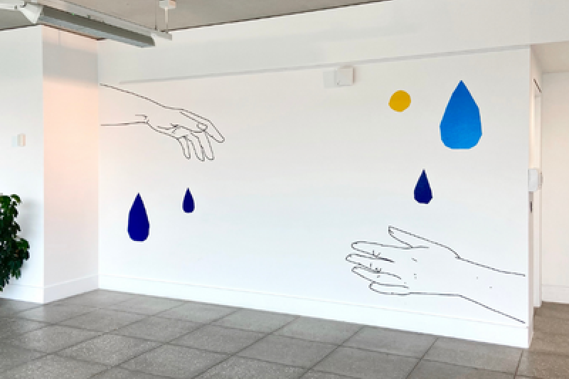 a white wall with a art piece of two hands reaching to each other and raindrops