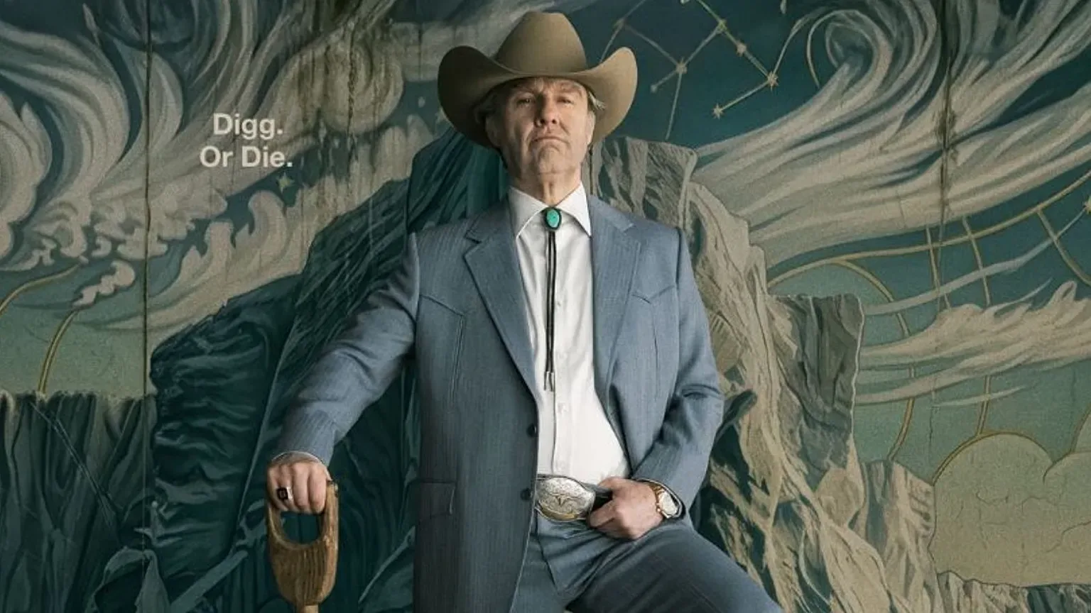 Man in a blue suit and cowboy hat holding a shovel