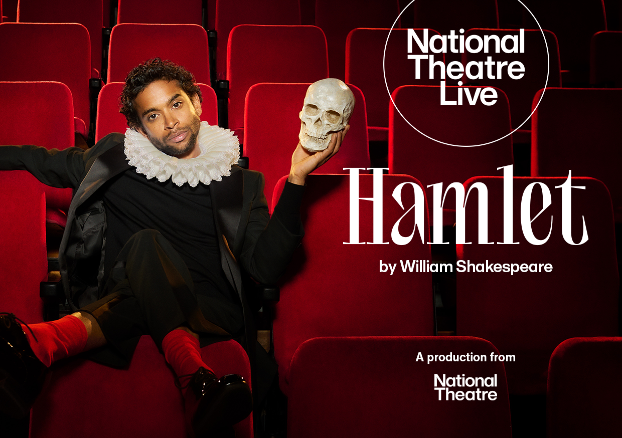 Photo of an actor dressed in a black suit with a white Elizabethan ruff, lounging in a theatre seat while holding a skull,