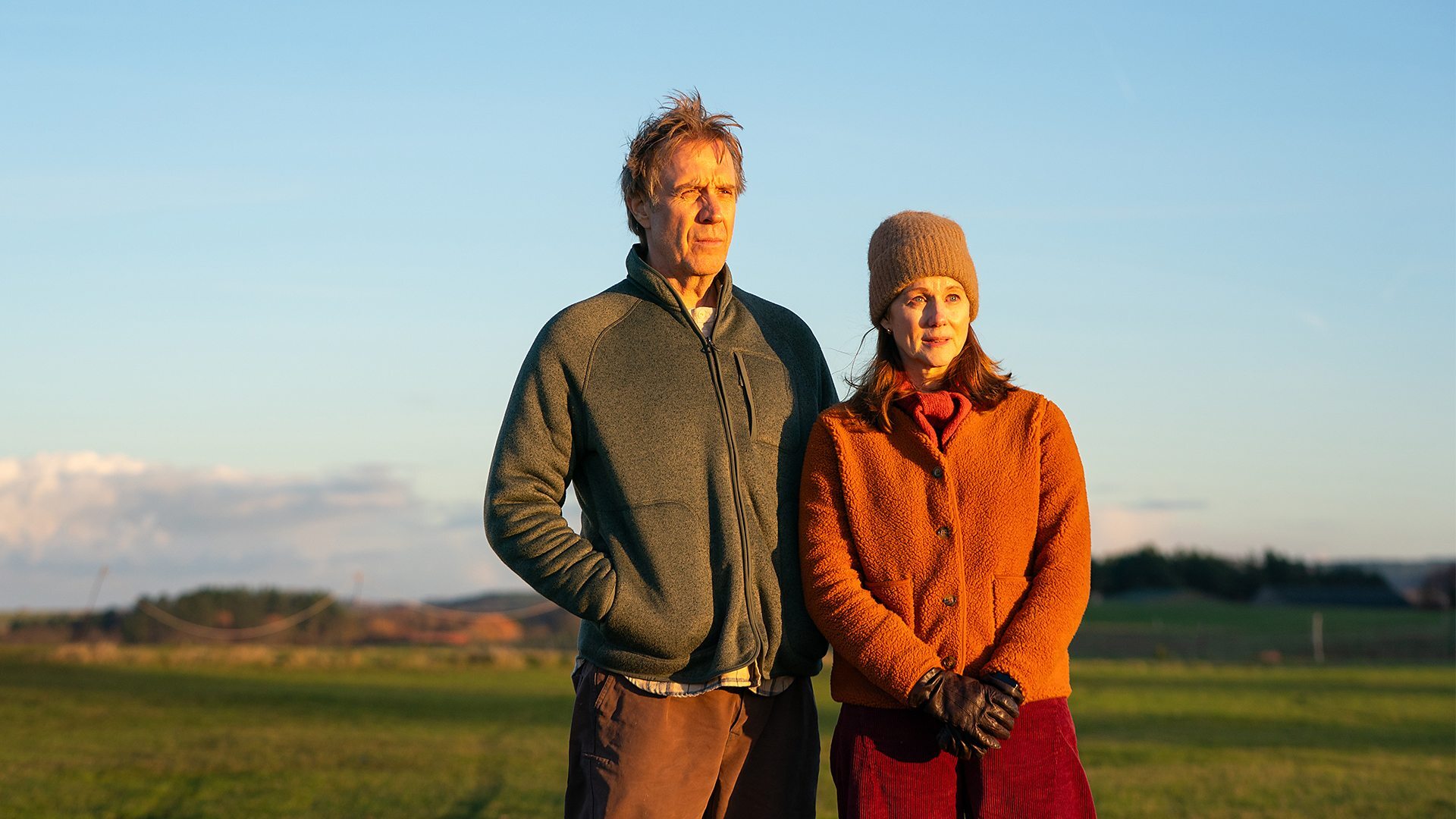 Man and woman standing outside in the countryside during sunset on a cold day
