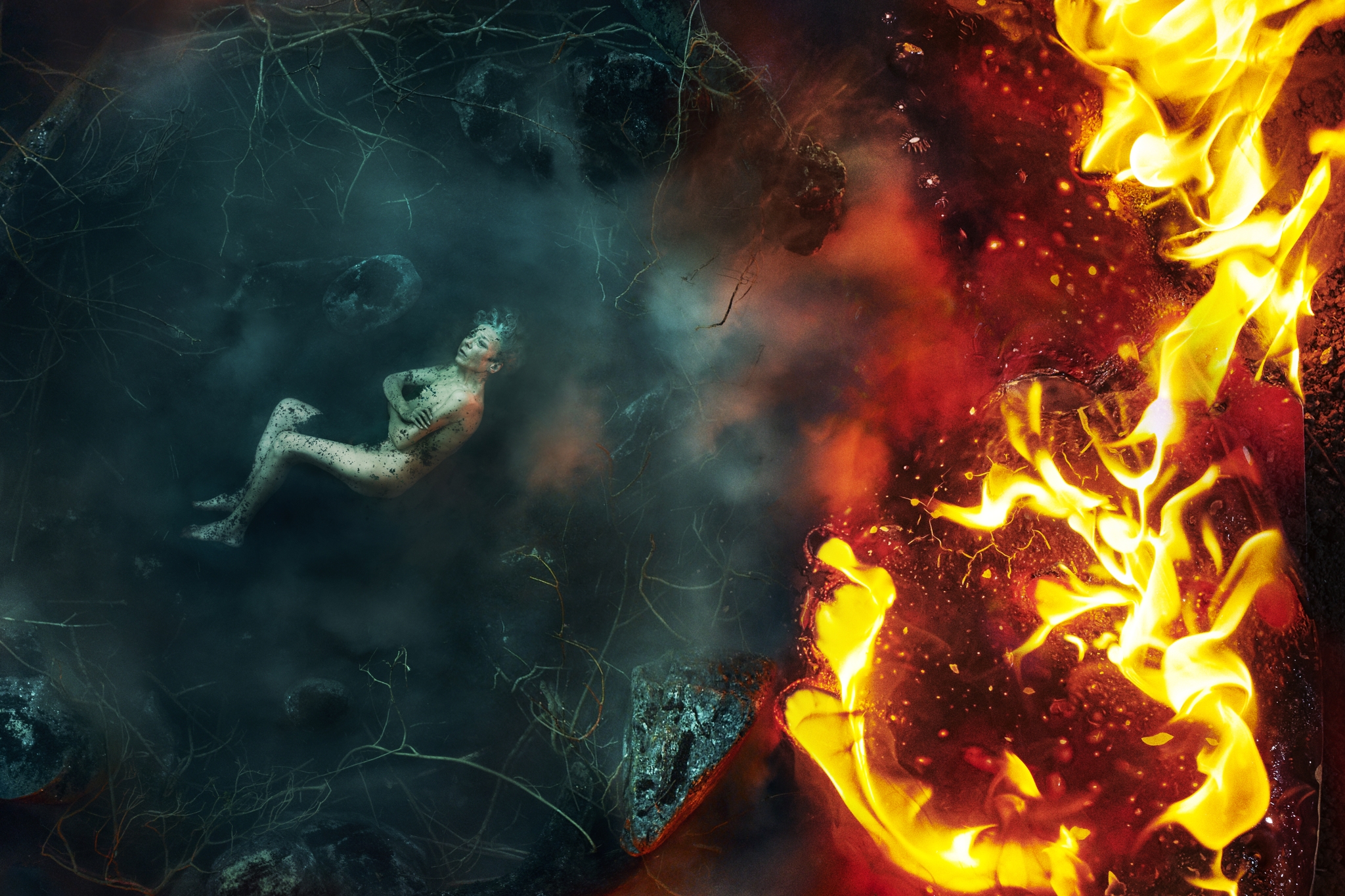 A surreal image showing a figure lying in a dark, misty environment on the left, while bright, intense flames burn vividly on the right
