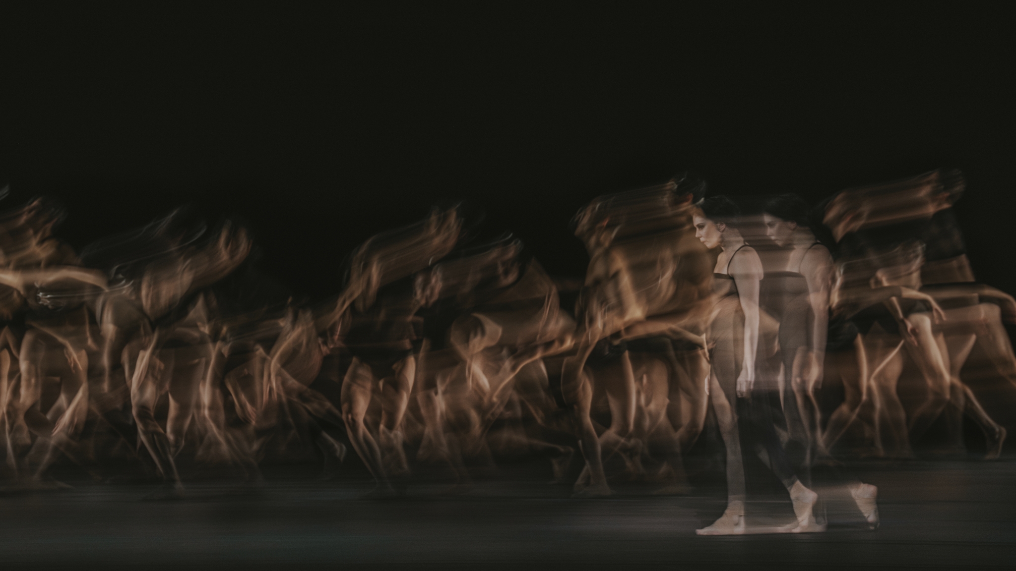 A blurred motion image of dancers performing on stage